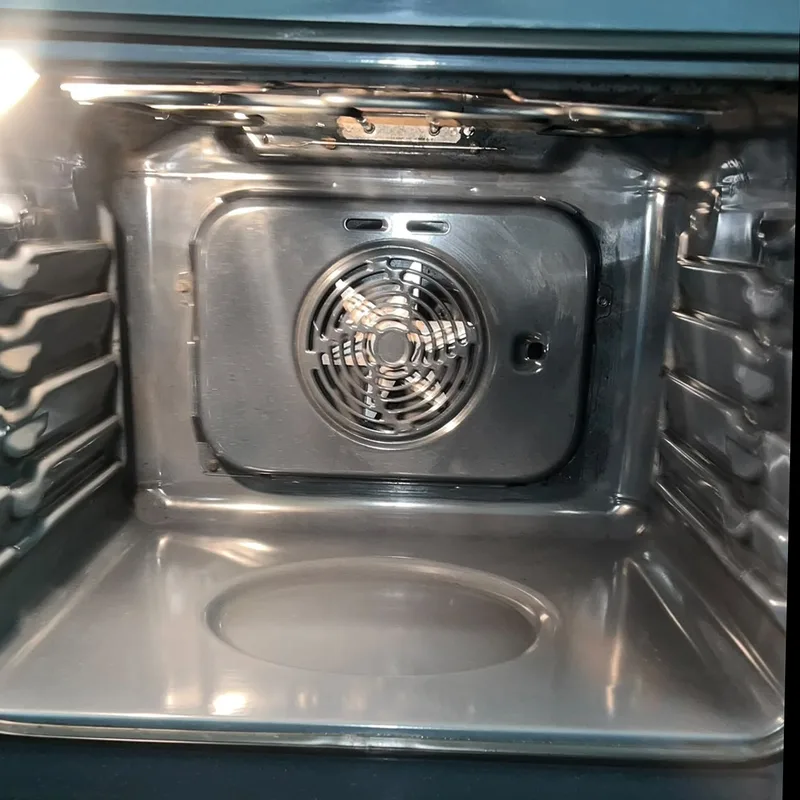 After: the same oven cleaned, floor, walls and fan cover spotless