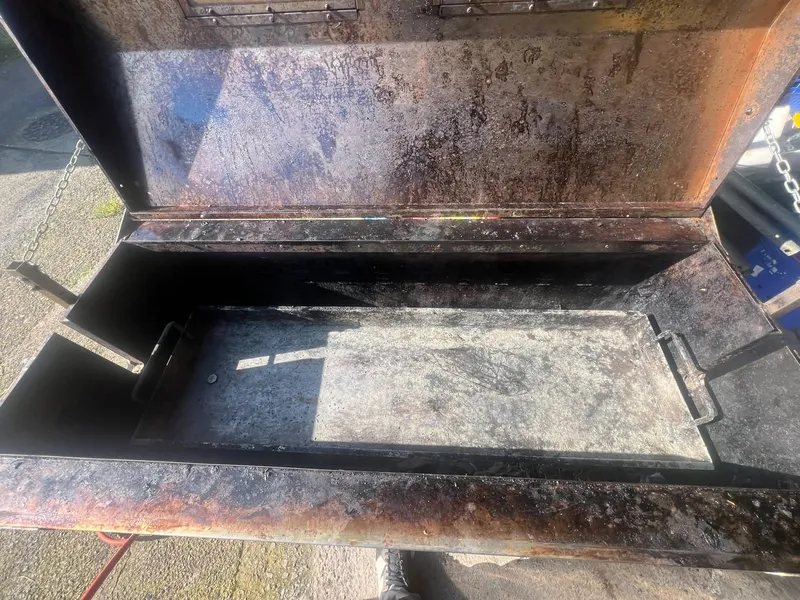 Lid and tray of a hog roast machine coated in burnt-on fat